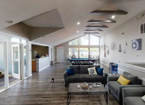 A living room with a glass table and grey couches.