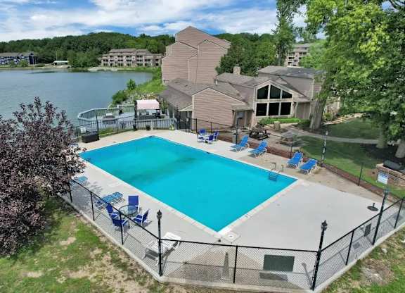 A large swimming pool surrounded by a fence and a house in the background.