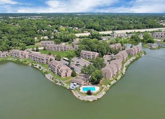 A bird's eye view of a resort with a swimming pool surrounded by water.