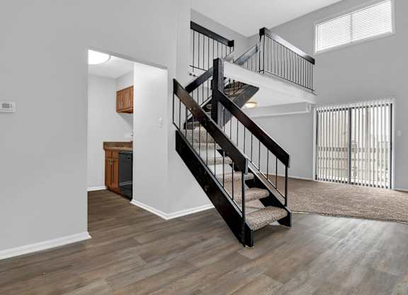 A wooden staircase with a metal railing leads to a second floor.