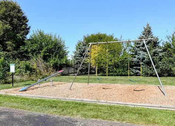 A playground with a slide and swings set in a grassy area.