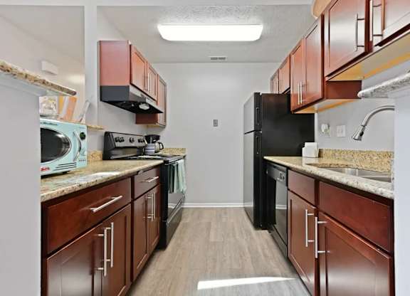 A kitchen with wooden cabinets and a black refrigerator.