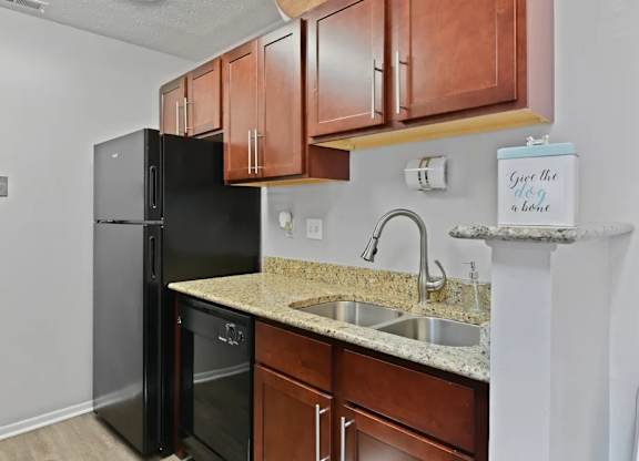 A kitchen with a black fridge and wooden cabinets.