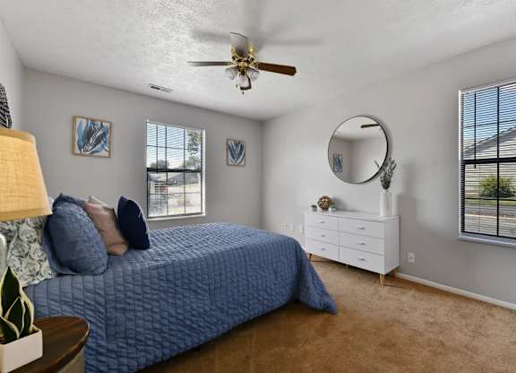A bedroom with a blue bedspread and a white dresser.