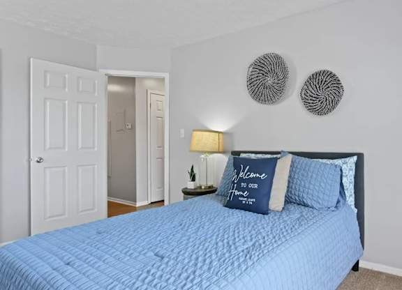 A bedroom with a blue bedspread and a sign that says "Welcome to DORIA".