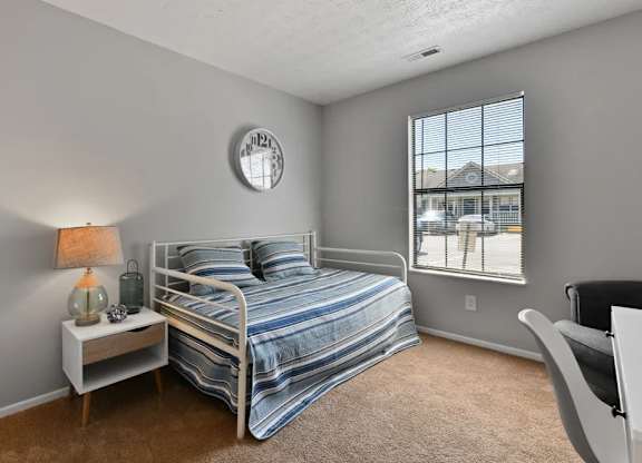A bedroom with a bed, nightstand, and chair.