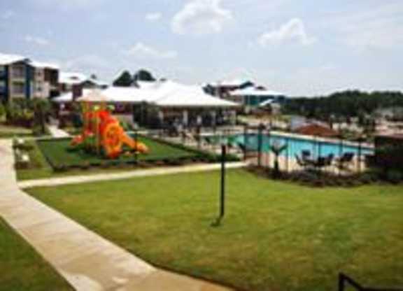 A playground with a slide and a pool in the background.