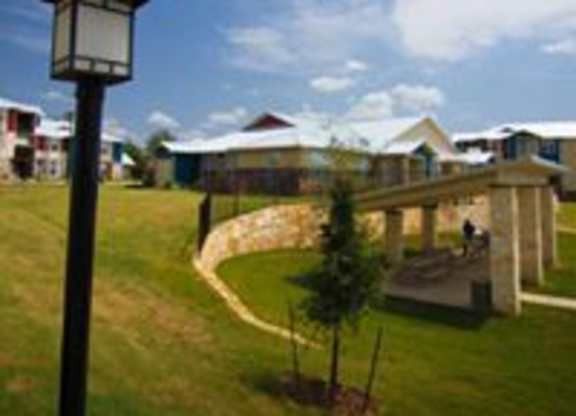 A grassy area with a lamp post and a building in the background.