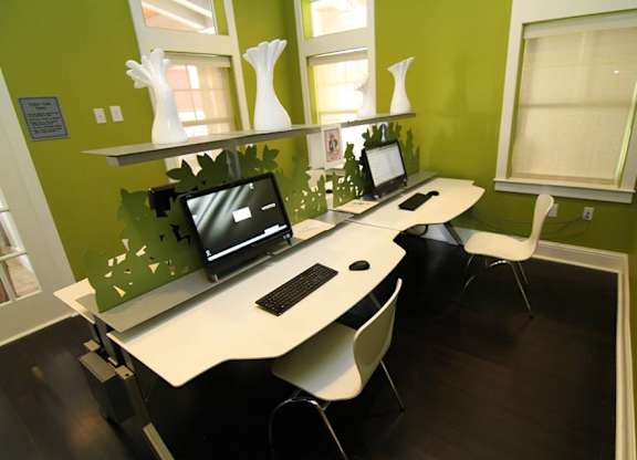 A room with a green wall and a white desk with a computer on it.