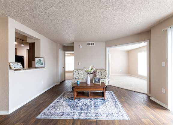 A living room with a blue rug and a wooden coffee table.