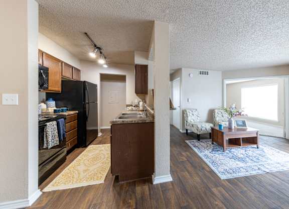A kitchen with a black refrigerator and wooden cabinets.