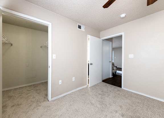 A room with a carpeted floor and a ceiling fan.