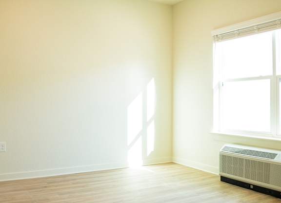 A room with a window and a wall-mounted air conditioner.