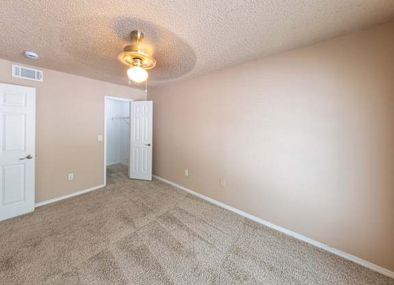 A room with a carpeted floor and a ceiling fan.