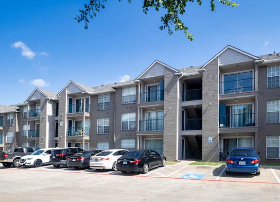A parking lot with cars and apartment buildings in the background.