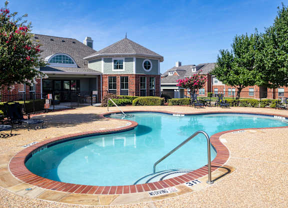 A swimming pool with a brick border and a slide.