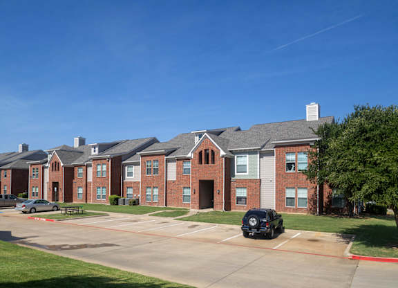 A row of red brick houses with a black car parked in front of the first house.
