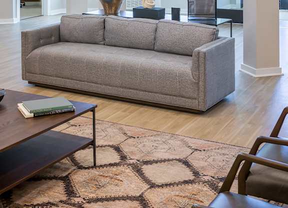 A grey couch sits in a well lit room with a coffee table in front of it.