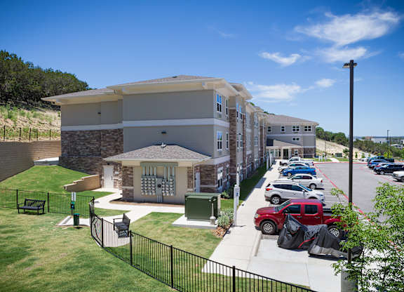 A sunny day at a residential complex with cars parked in the lot.