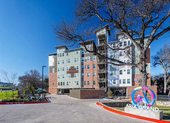 A tall apartment building with a sign that says "ARIA GRAND" in front of it.