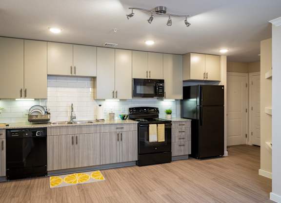 A modern kitchen with black appliances and wooden floors.