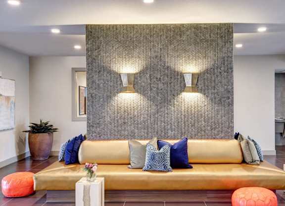 A modern living room with a gold sofa and a grey textured wall.