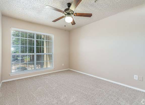 A room with a ceiling fan and a window with blinds.