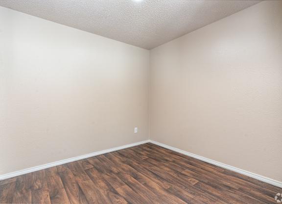 A room with wooden flooring and white walls.