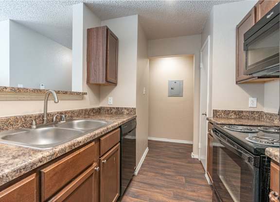 A kitchen with a sink, stove, and microwave.