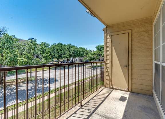 A balcony with a view of a road and trees.