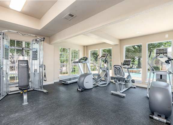 A spacious gym with a variety of equipment including treadmills, elliptical machines, and a weight machine.