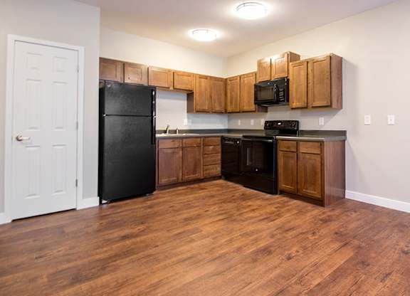 A kitchen with black appliances and wooden cabinets.