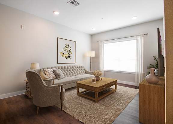 A living room with a grey couch, a wooden coffee table, and a painting on the wall.