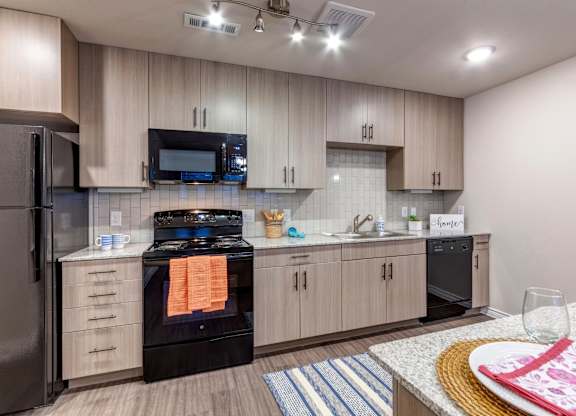 A modern kitchen with a black stove top oven and a black refrigerator.