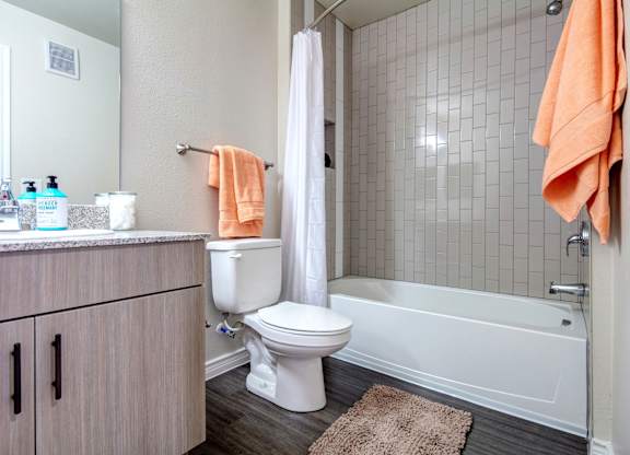 A white toilet sits next to a white bathtub in a bathroom.