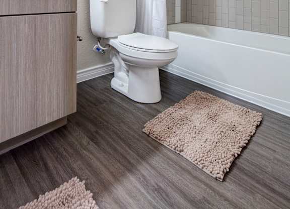 A white toilet with a white curtain and a towel on the side.