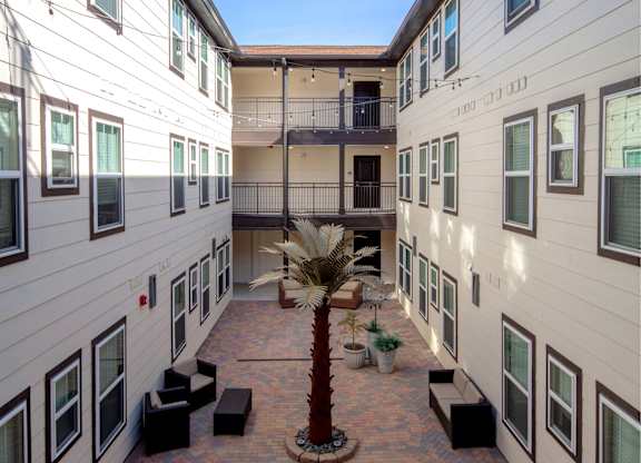 A courtyard with a tree and benches surrounded by buildings.