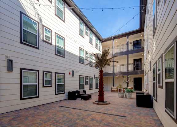 A courtyard with a palm tree and a balcony.