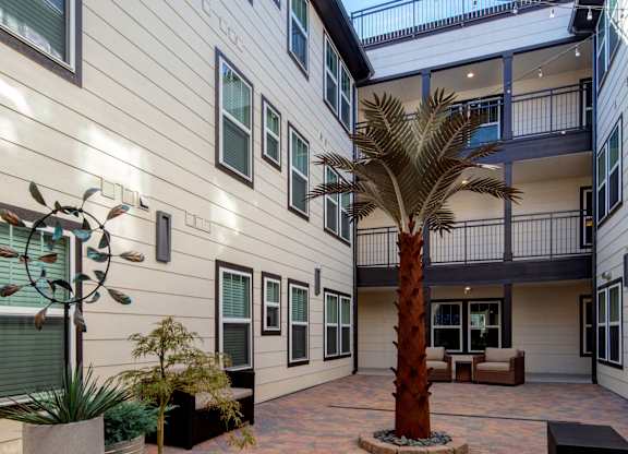 A courtyard with a palm tree and potted plants.