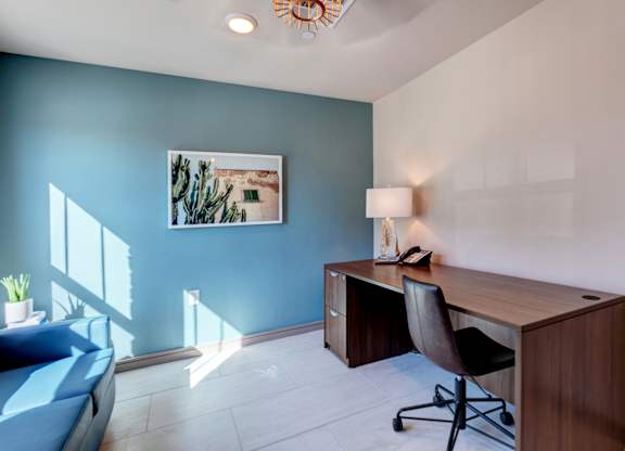 A room with a blue wall and a wooden desk with a chair.