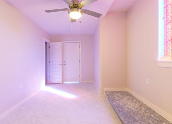 A room with a ceiling fan and a light on.