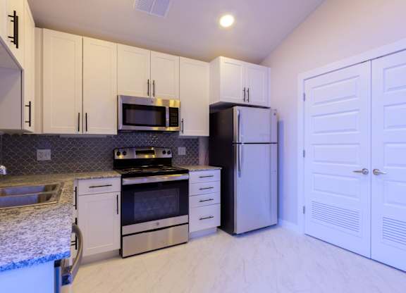 A kitchen with white cabinets and appliances.