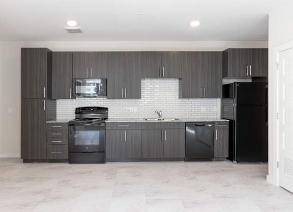 A modern kitchen with dark wood cabinets and black appliances.