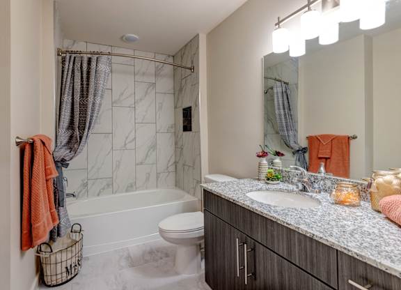 A bathroom with a marble tile shower and a white toilet.