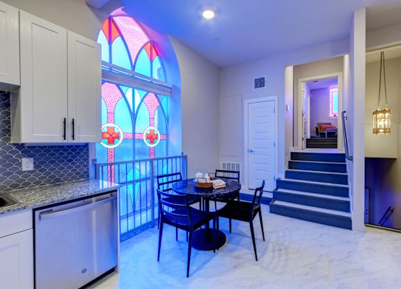A kitchen with a table and chairs and a stained glass window.