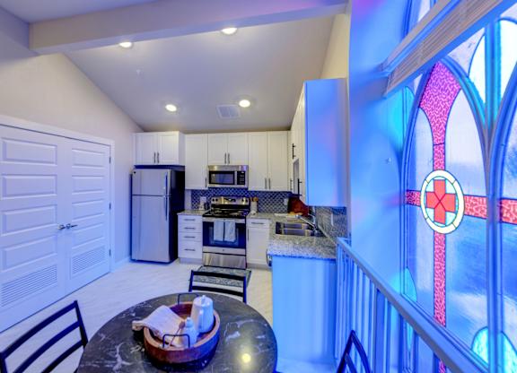 A kitchen with a table and chairs in front of a stained glass window.