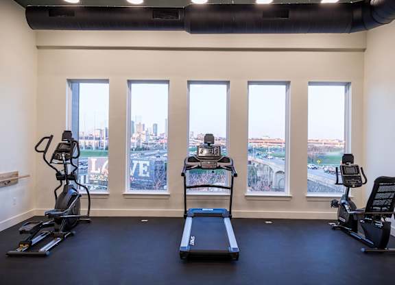 A gym with treadmills, exercise bikes and a view of the city.