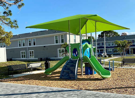 A playground with a green slide and a green canopy.