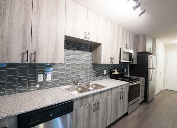 A kitchen with a sink, stove, and refrigerator.