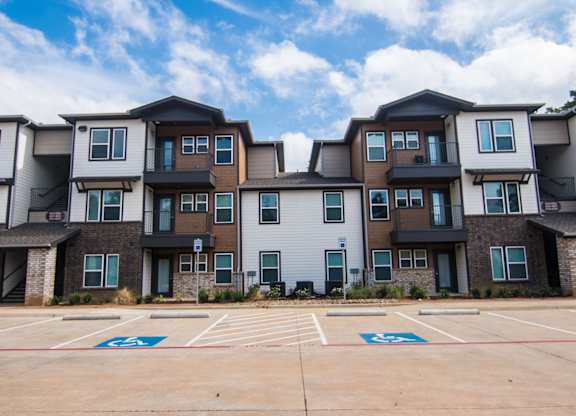 Apartment building with a parking lot in front.